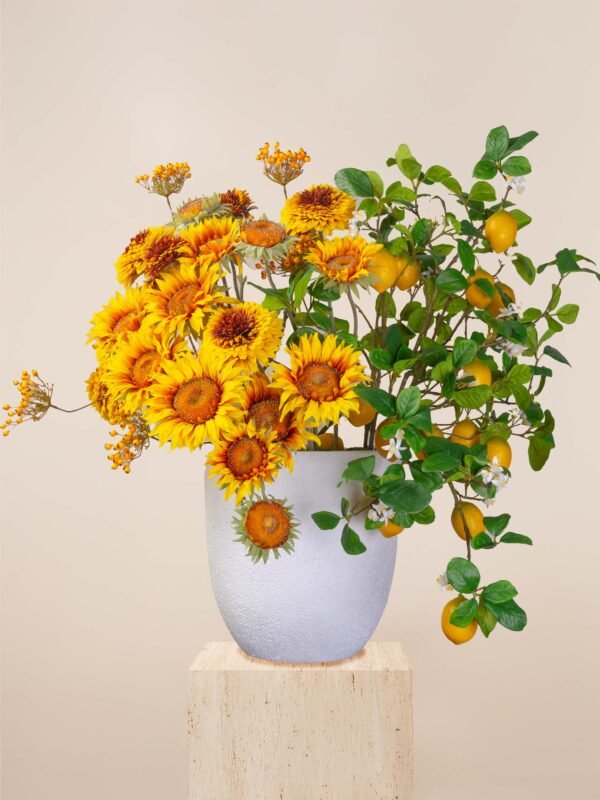 Artificial sunflower arrangement in Dubai with golden blooms, lemon sprays, and greenery in a white vase.