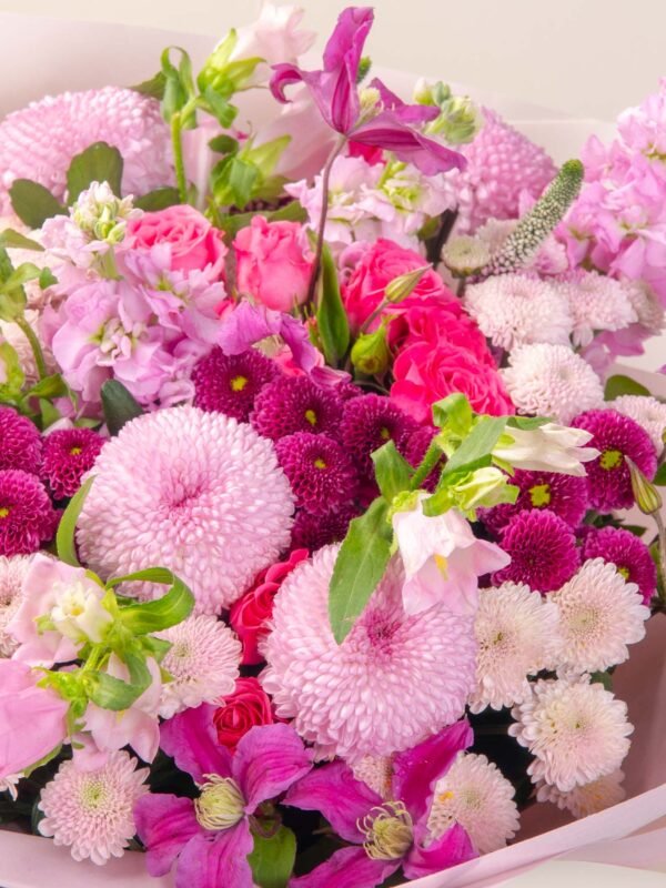 Close-up of pink flower bouquet showing chrysanthemums, clematis, and roses.