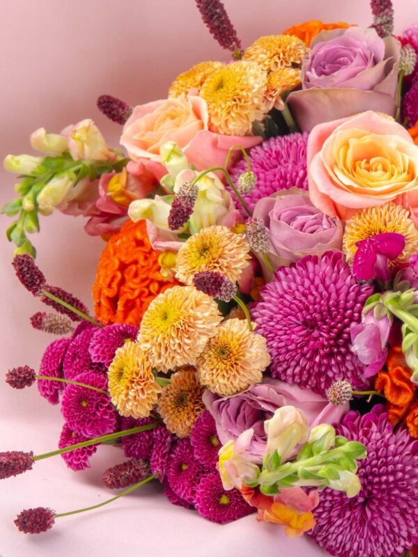 Close-up of orange celosia, peach roses, and pink chrysanthemums in luxury flower bouquet