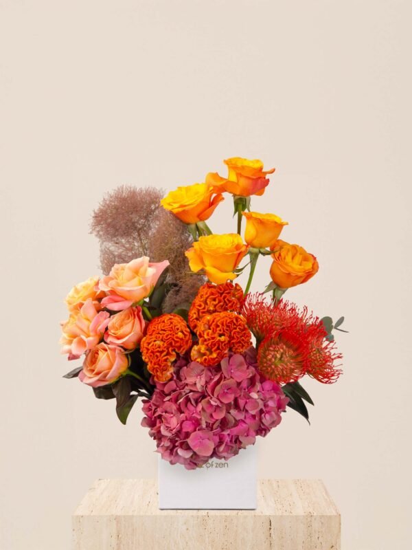 Warm tone flower box with orange roses, celosia, hydrangea, and nutans in a white Houz of Zen box.