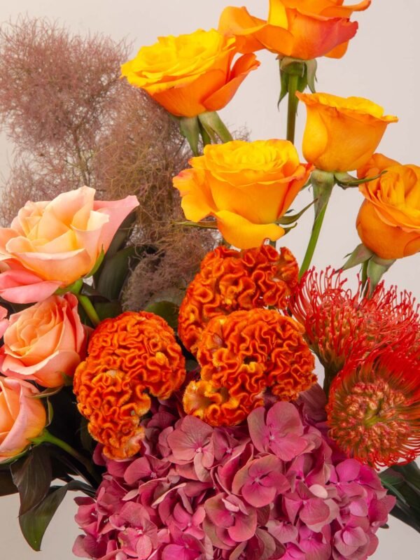 Orange roses and celosia details in warm tone flower box.
