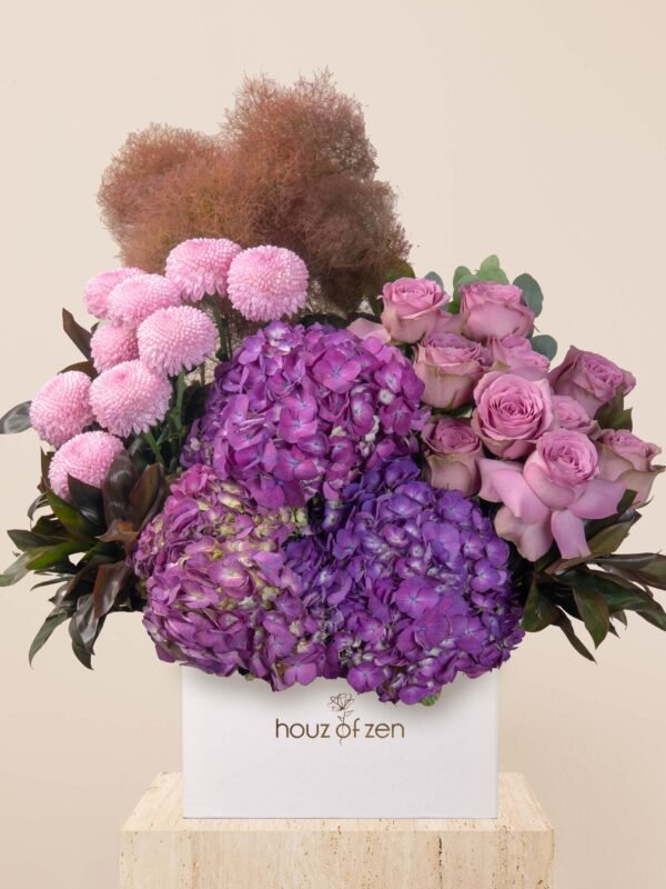 Violet flower box with lilac roses, purple hydrangeas, and pink chrysanthemums in a white box.