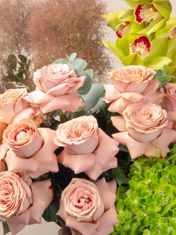 Close-up of fresh flower basketarrangement in Dubai with cappuccino roses, green cymbidium orchids, emerald hydrangeas, and eucalyptus.