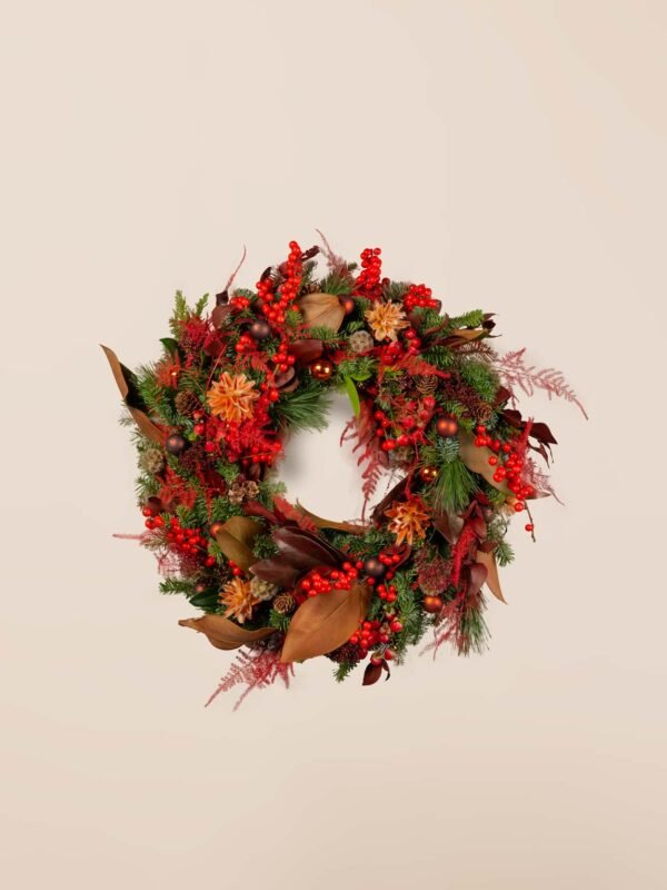 Fresh red holiday wreath with berries, pine foliage, magnolia leaves, and festive red botanicals.